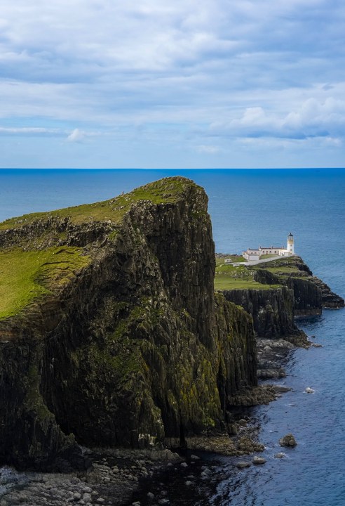 A lighthouse beyond a steep coastal cliff