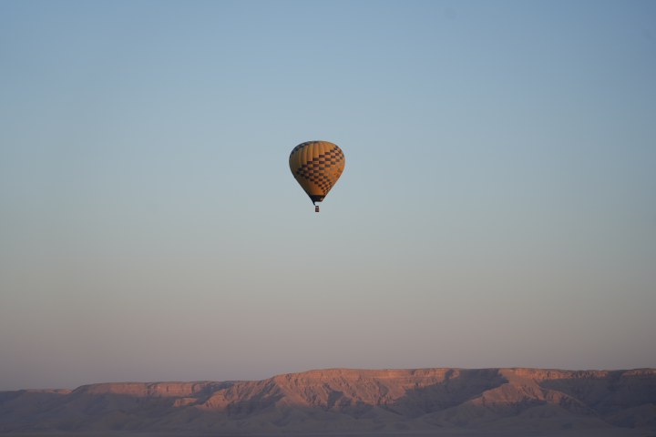 A lone hot-air balloon above a softly lit ridge