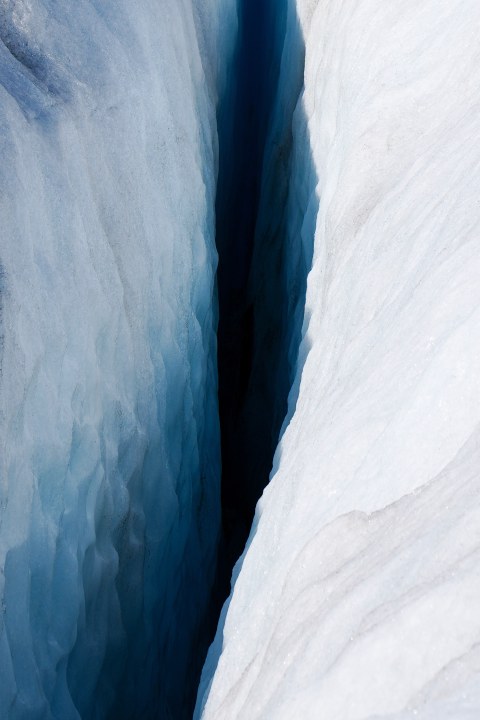 A deep blue crevasse between white glacier walls